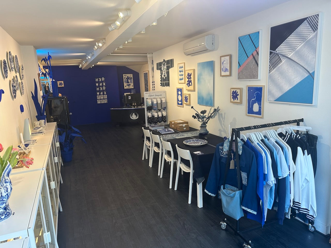 A modern store interior with blue and white decor, wall art, and clothing rack.